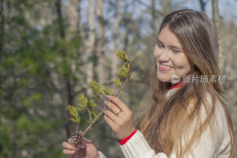 一个寒冷的感恩节/圣诞节秋天的早晨/下午，一位年轻的拉丁妇女在松冠森林中间休息时的画像。